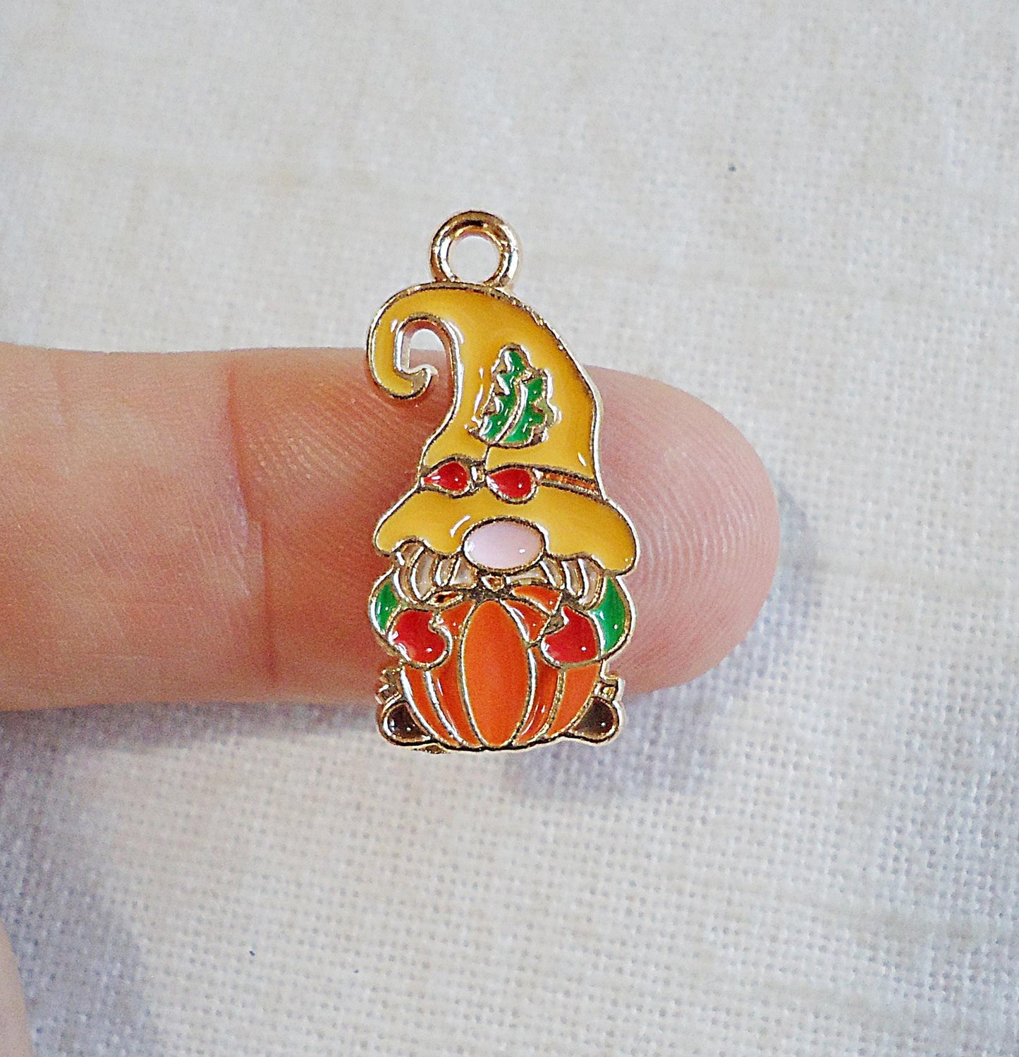 gnome charm with a yellow hat holding an orange pumpkin