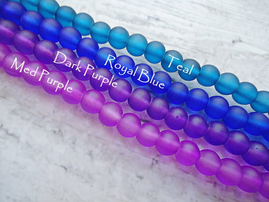 Three strands of colored beads labeled 'Dark Purple', 'Royal Blue', and 'Teal' on a textured white background.