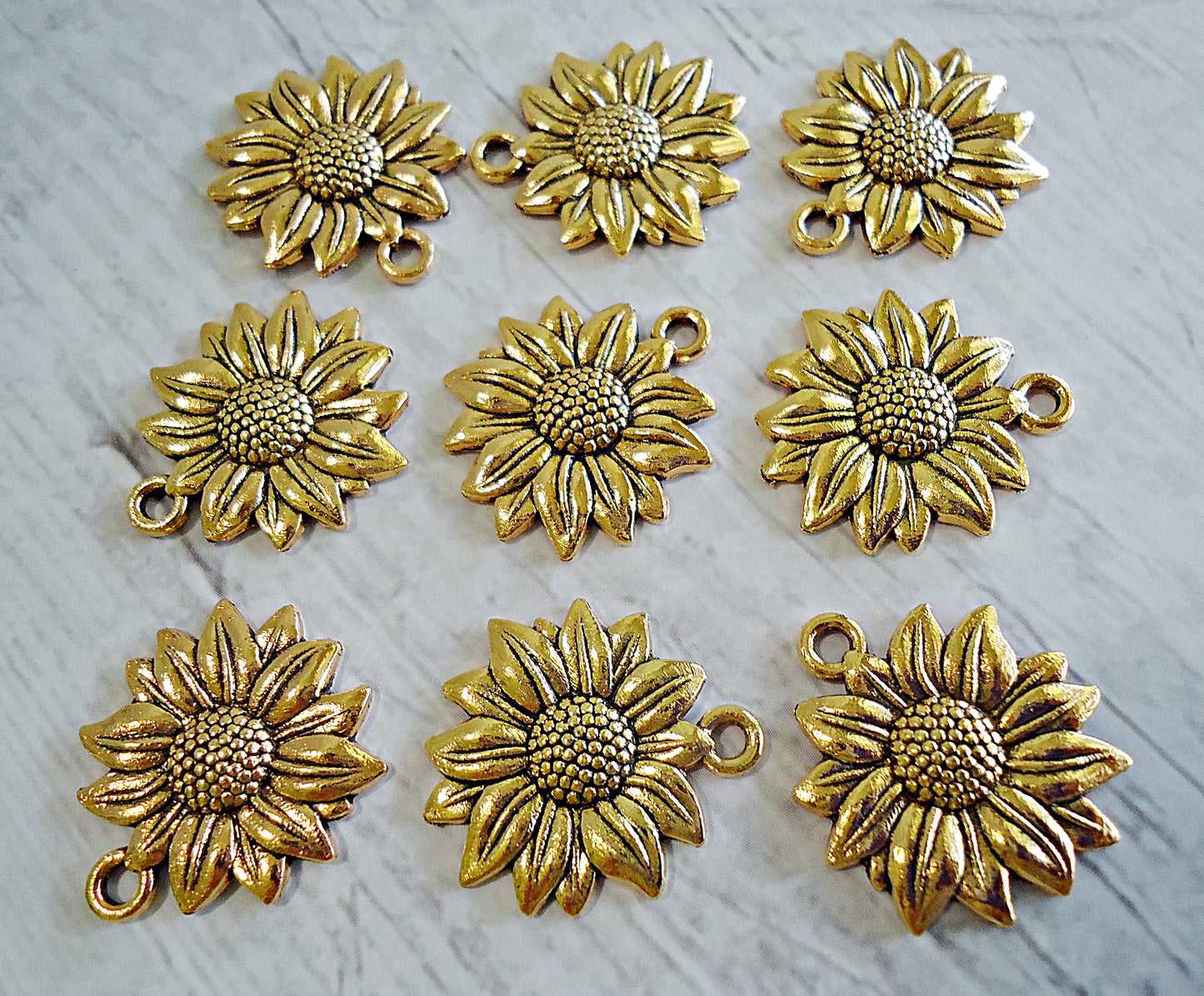 Gold sunflower-shaped charms on a light gray background