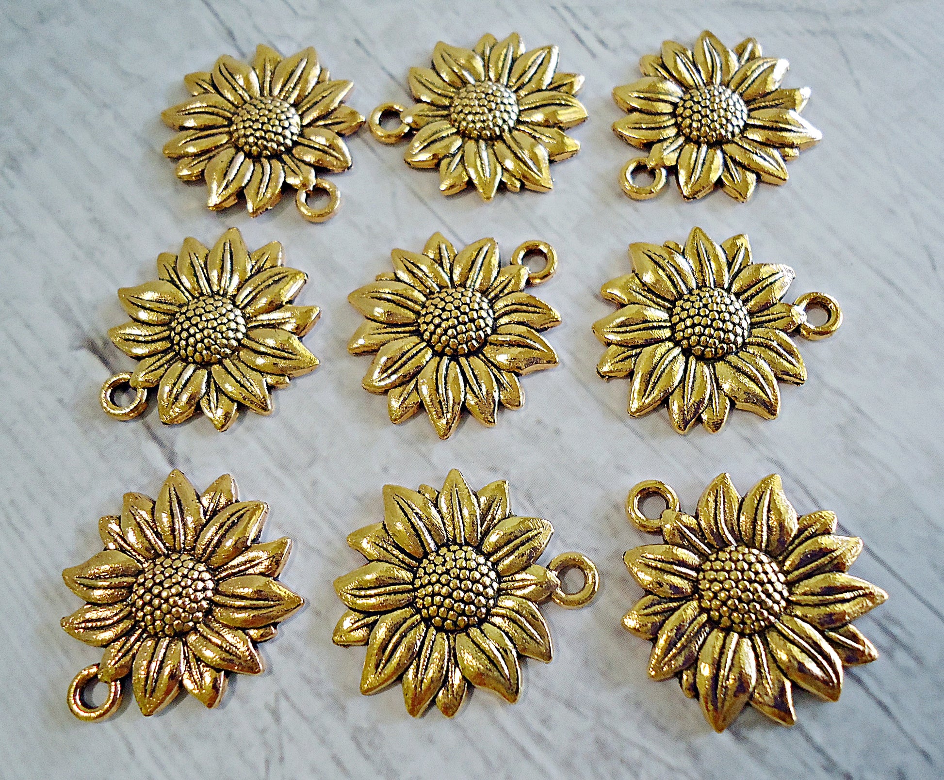 Gold sunflower-shaped charms on a light gray background